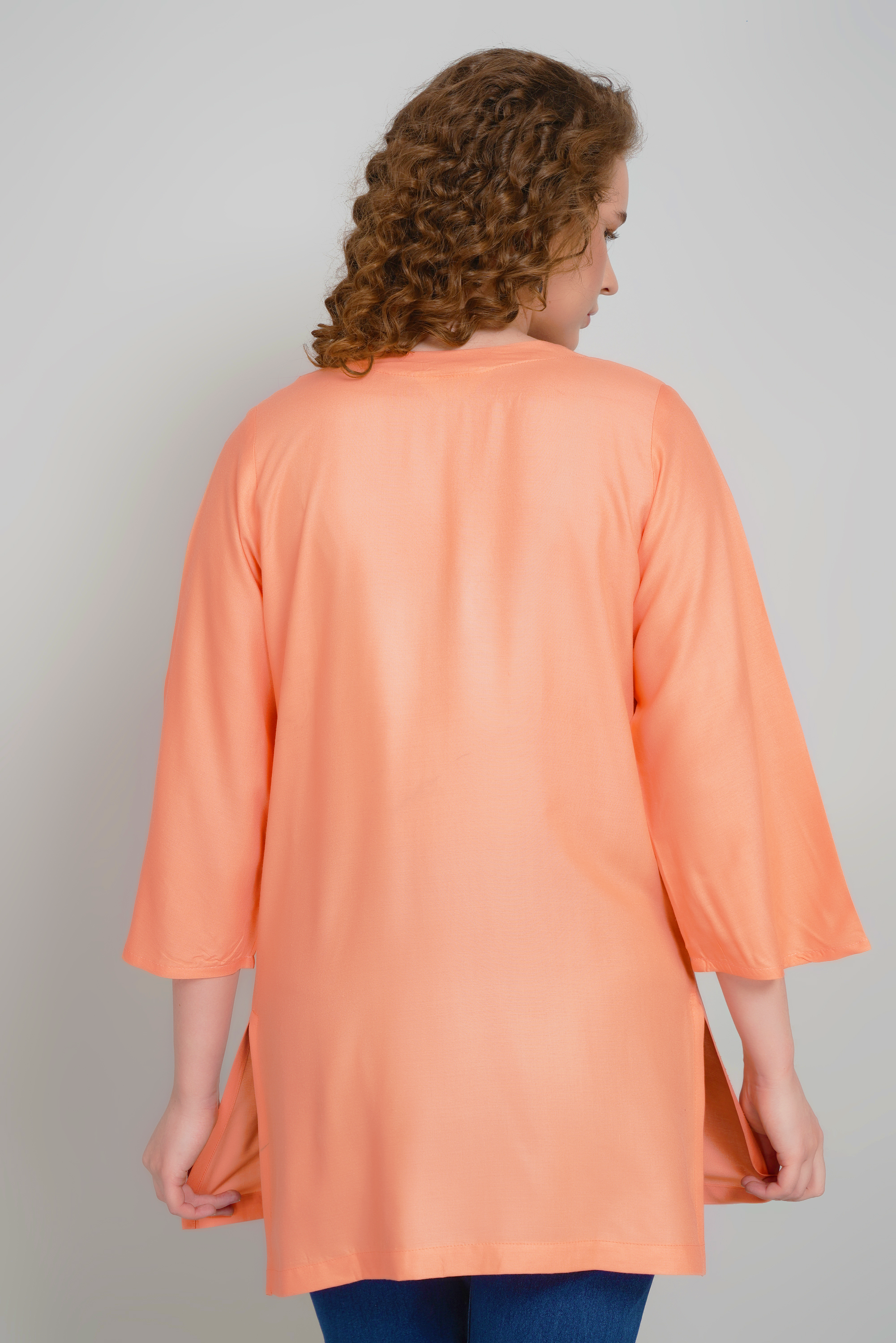 Women's peach-orange short kurti, back view, three-quarter sleeves, plain hem