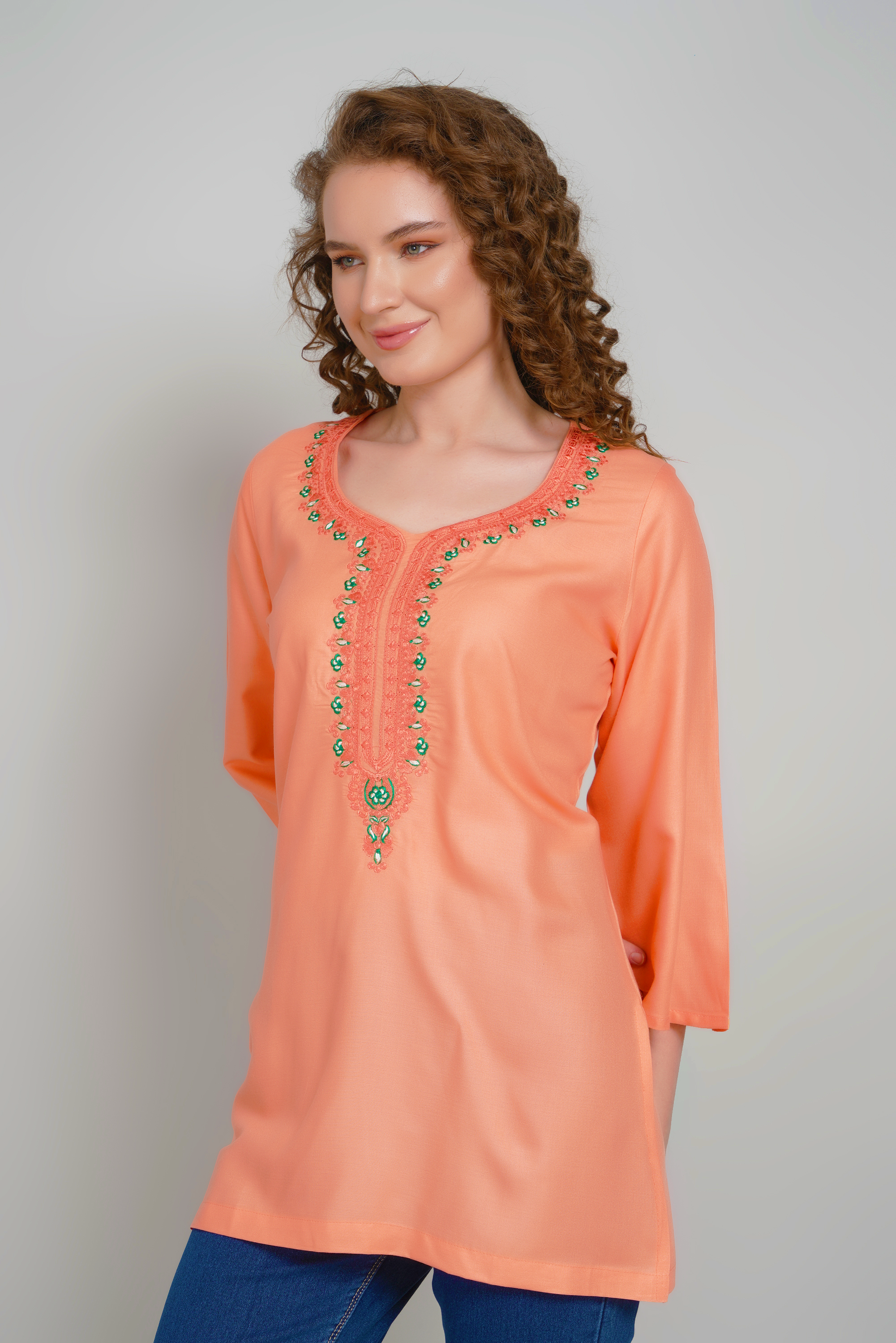 Women's peach-orange short kurti with detailed embroidered V-shaped neckline, three-quarter sleeves