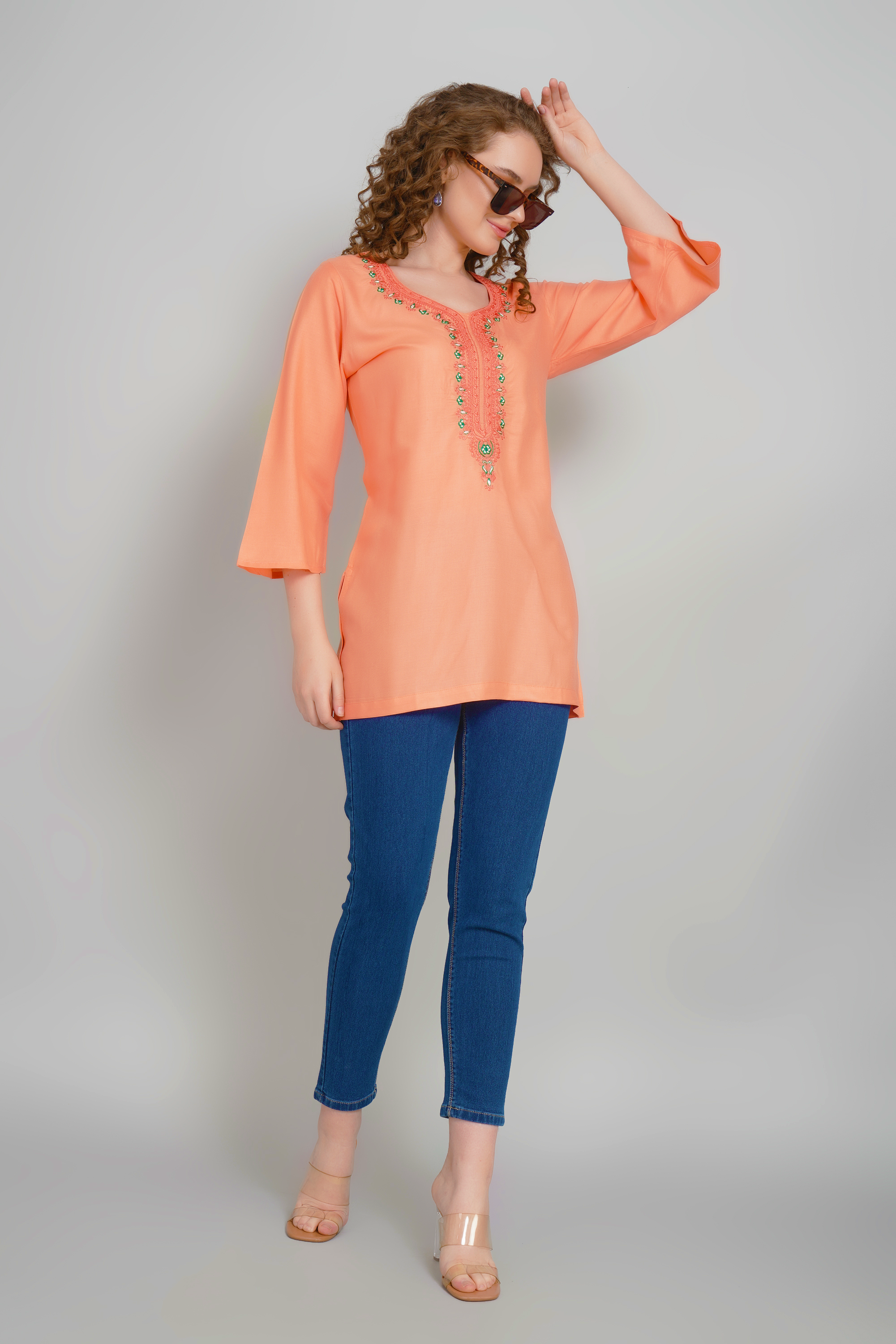 Women's peach-orange short kurti, side view, embroidered neckline, three-quarter sleeves